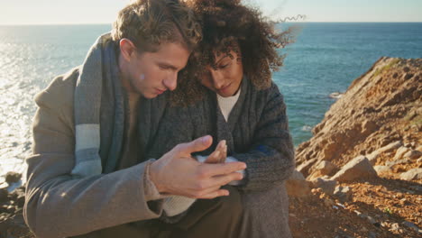 peaceful couple sitting cliff touching hands at evening closeup. tender pair
