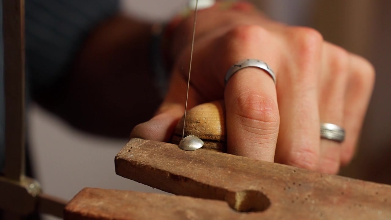 A craftsman focuses on precision while operating a scroll saw, cutting patterns into a wooden piece.