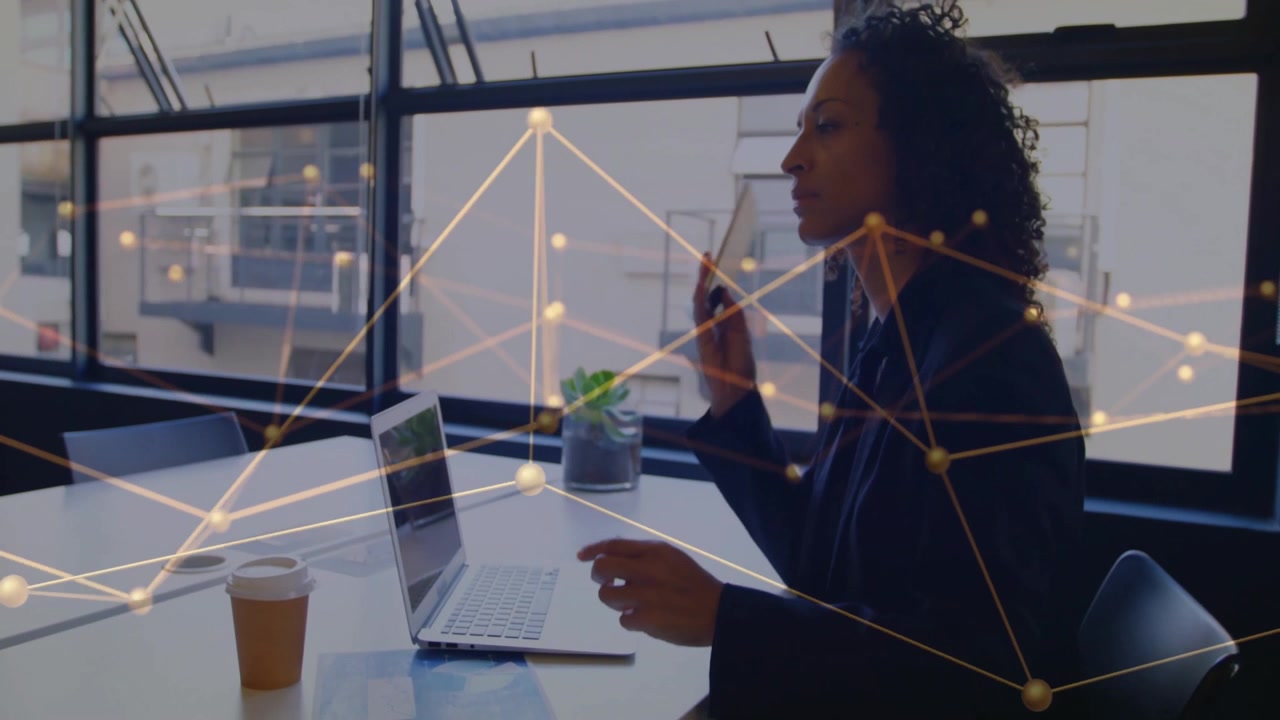 Business woman holding smartphone hovering over laptop in boardroom, showing network overlay