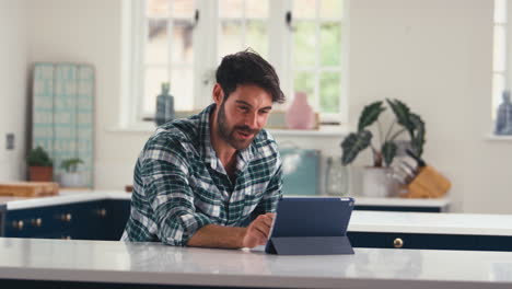 Man-Using-Digital-Tablet-At-Home-To-Make-Video-Call