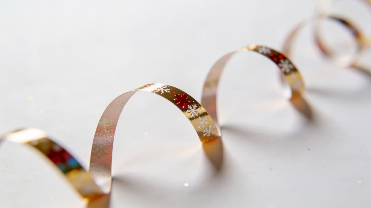 Nastro metallico in movimento con fiocco di neve rosso oro su tappetino bianco, messa a fuoco che affina l'arco centrale, glitter.
