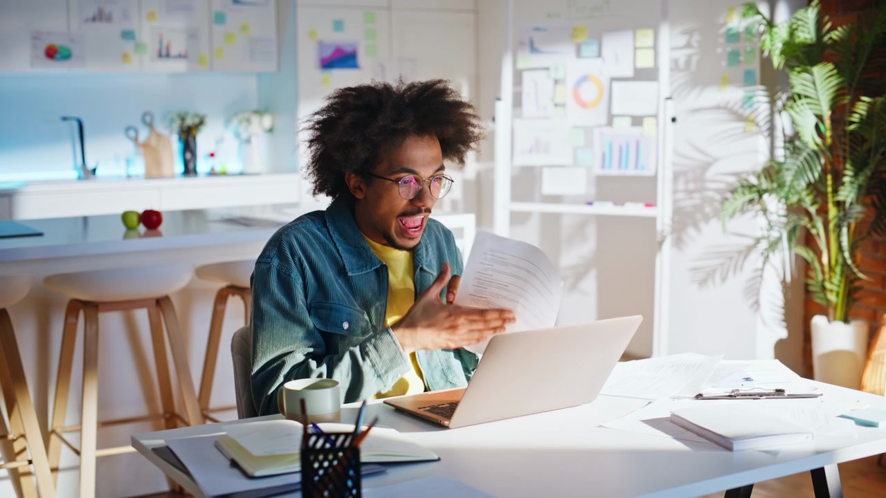 Freelancer talking video call laptop home office. Man discussing project papers.