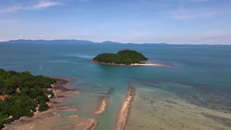 An-aerial-view-of-an-island-covered-with-green-forest-with-a-background-of-clear-sky-near-Koh-Samui,-Thailand