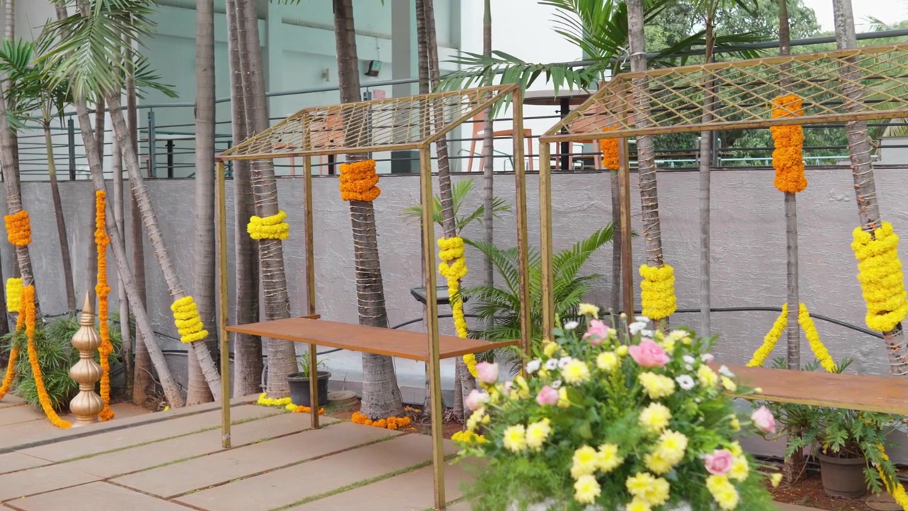Rangkaian bunga dan karangan bunga marigold menghiasi penataan lokasi pernikahan luar ruangan.