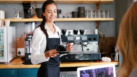 camarera sirviendo una taza de café a una mujer