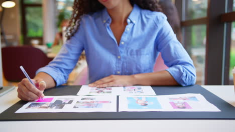 mujer de negocios sentada en un escritorio en una oficina de plan abierto aprobando o verificando pruebas o diseños de diseño