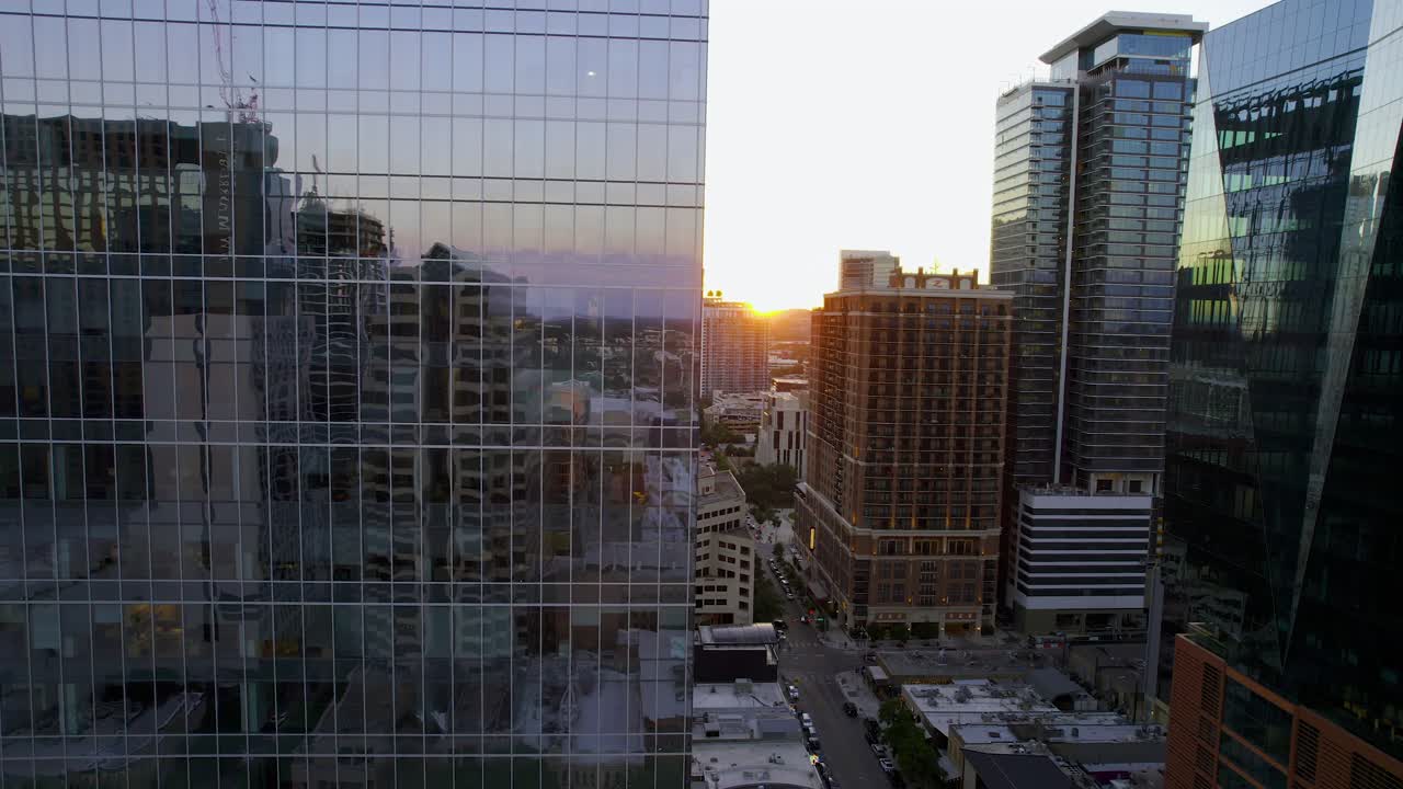 vista aérea volando en medio de un rascacielos reflejado, revelando la cuarta calle y el sol del atardecer en austin, estados unidos - dando vueltas, disparo de drones