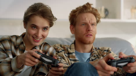 Joyful-wife-holding-gamepad-fighting-confused-redhead-husband-at-home-closeup.