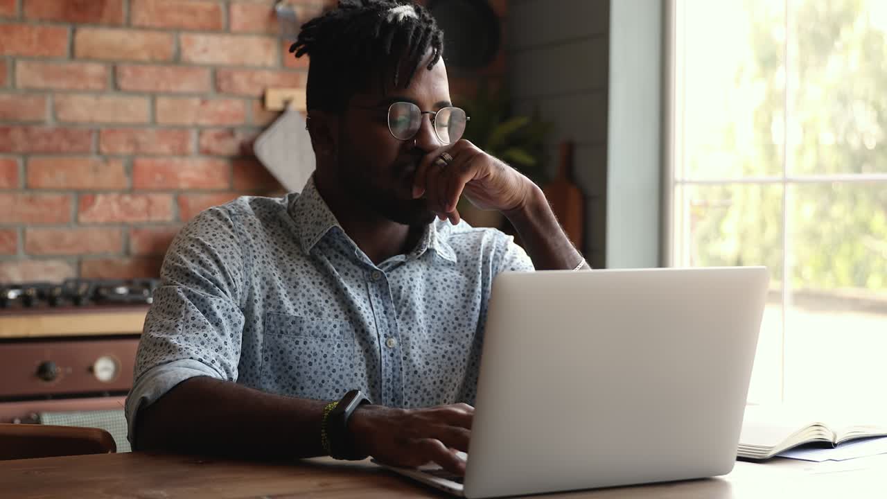 un hombre africano preocupado usa una computadora portátil para leer noticias desagradables en el correo electrónico.