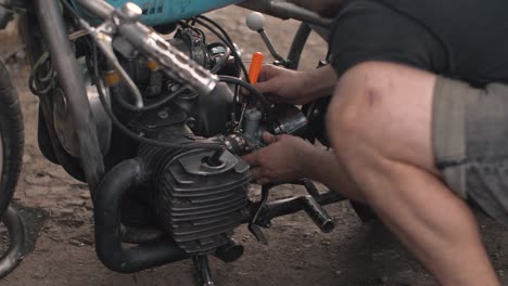 the mechanic man tunes the engine, mechanic fixes old motorcycle engine