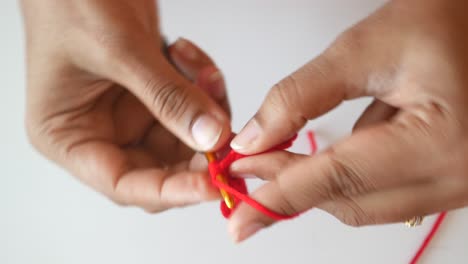 woman's hands crocheting with red yarn