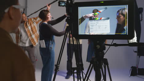 close up of female film director and assistant watching actors shooting movie or video scene in studio