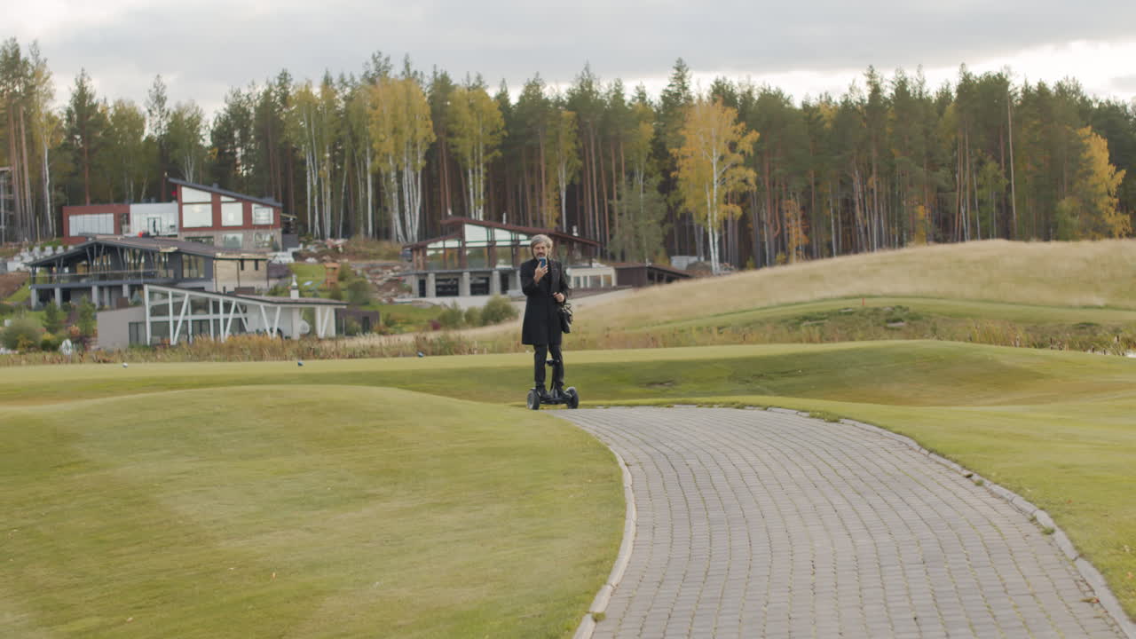 Man standing on a golf course with modern luxury homes and a forest in the background