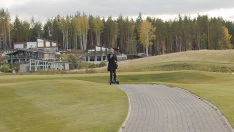 man standing on a golf course with modern luxury homes and a forest in the background