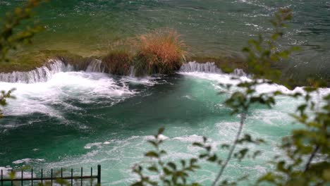 view of a waterfall flowing from a large blue pond to another blue pond in krka national park in croatia