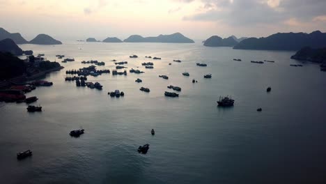 Port-of-Ha-Long-Bay-Vietnam-during-sundown-with-dozens-of-commercial-ships,-Aerial-flyover-shot