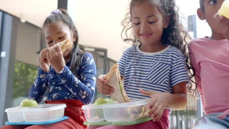 in school, three young biracial girls are enjoying lunch