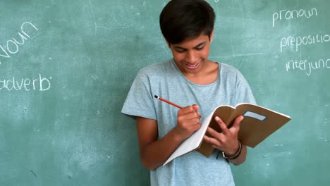 attentive schoolboy doing homework in classroom