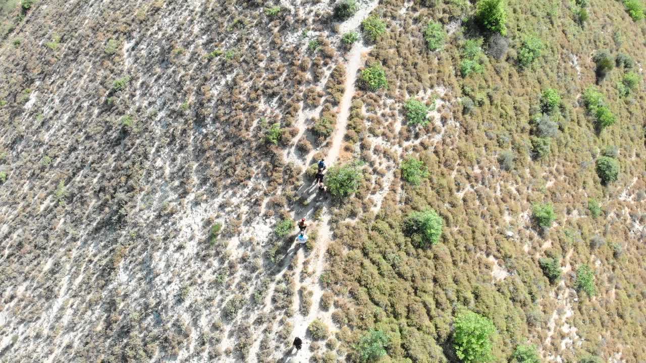 Adventurous hikers explore Lebanon's breathtaking mountain trails leading to an eerie ghost town. Stunning aerial views of the rugged landscape and hiking path through the Lebanese mountains