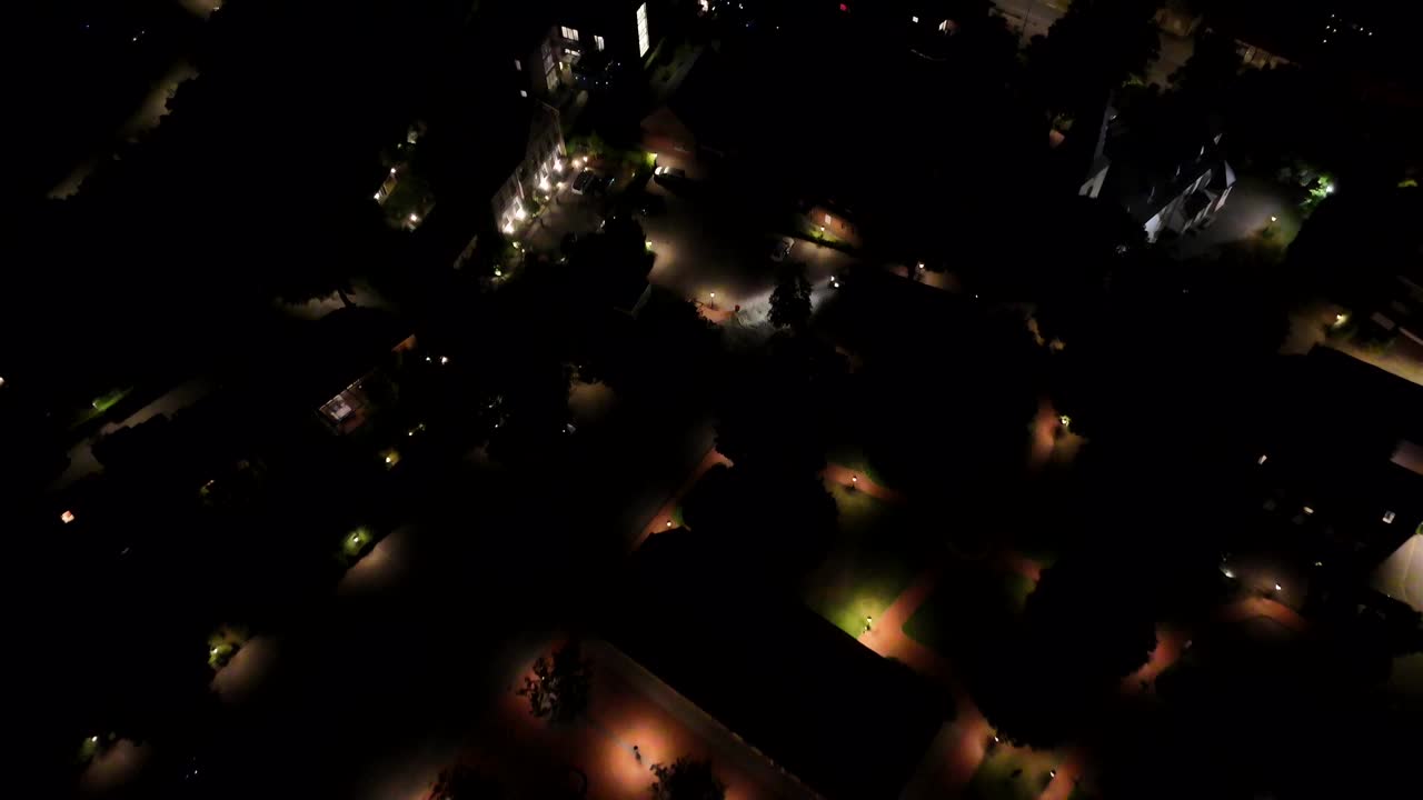 Warm lighting lantern of historic square in American town. Aerial flyover shot by night. Car parking after arriving city. Top down shot. Peaceful American town scene