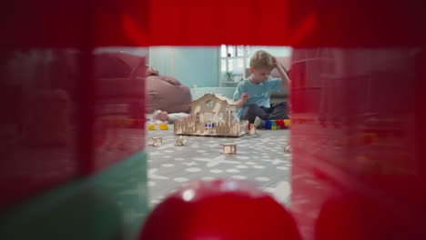 blond toddler plays with toys and blocks sitting on floor