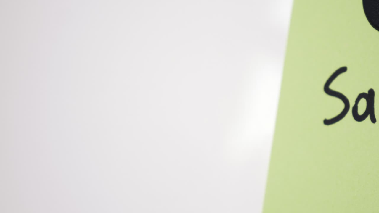 Pan reveal of Salary text on green note held by magnet on whiteboard with selective focus