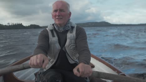 fisherman rowing on rough lake dramatic slow motion shot