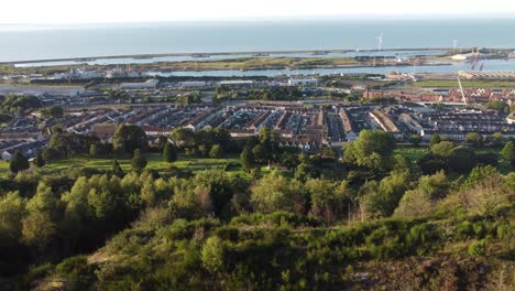 Sideways-Drone-with-Trees,-Houses,-Marina-and-Wind-Turbines