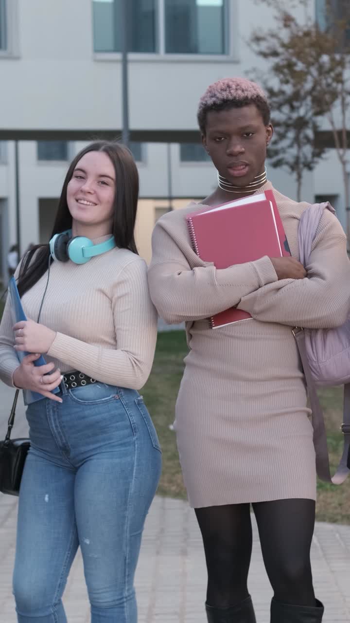 Coppia di studenti che sorridono alla fotocamera in piedi all'aperto nel campus universitario.