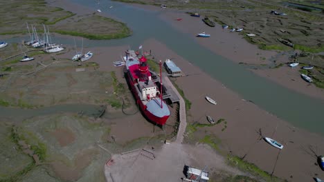 vista aérea alrededor de un buque faro atascado en el barro durante la marea baja, sunny tollesbury, reino unido - dando vueltas, disparo de drones