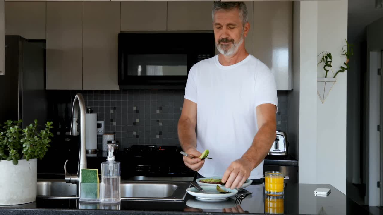 Mann bereitet Frühstück in der Küche zu 4K