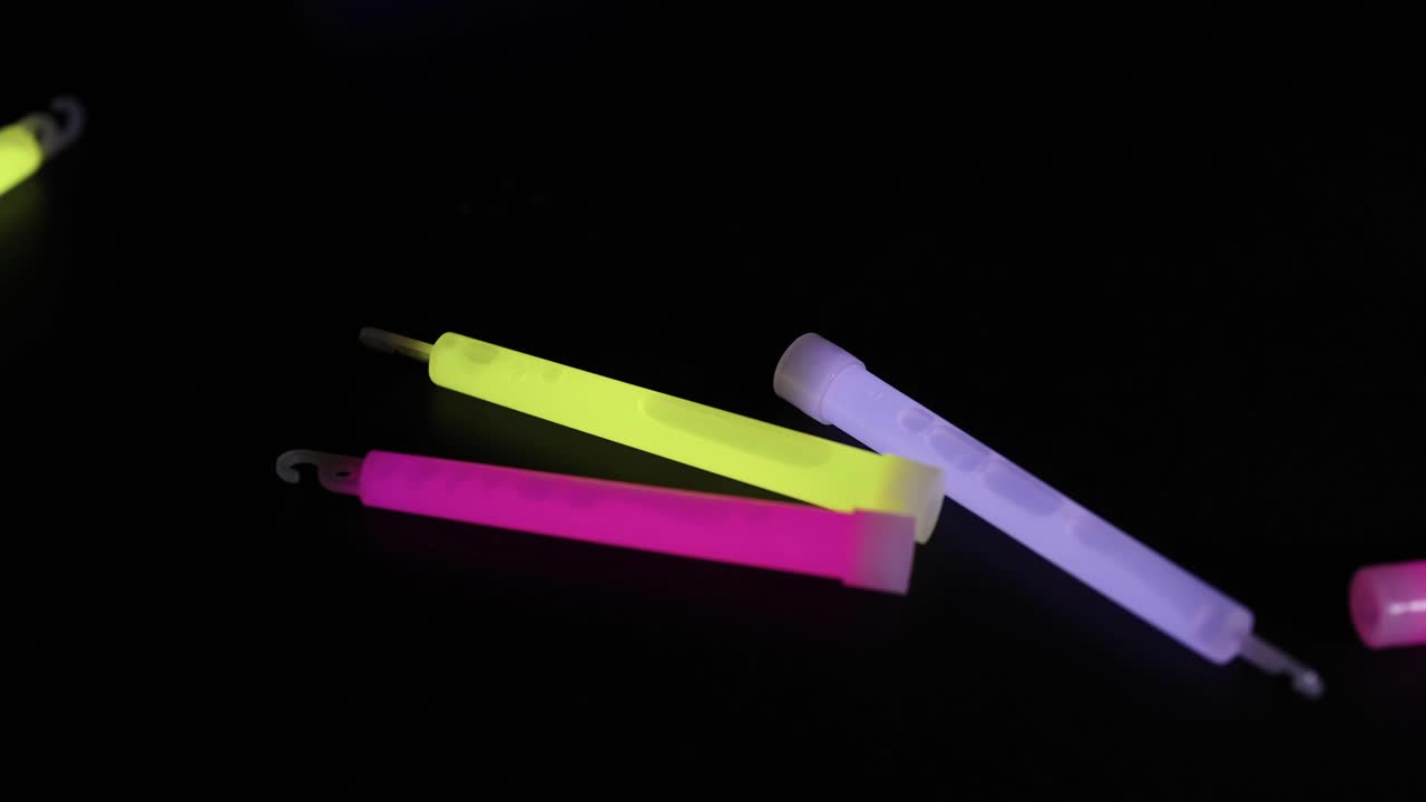 Glow sticks falling and landing on a dark surface