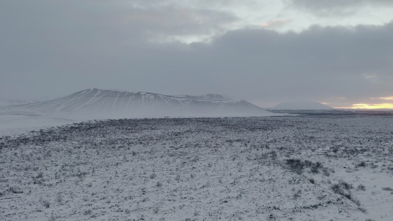 toma aérea ascendente del majestuoso cráter hverfjall cubierto de hielo y nieve durante el místico día de niebla