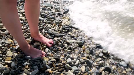 person's feet in the shallow water on the beach