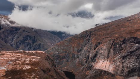 nubes blancas que se precipitan sobre la cordillera, los rayos del sol atraviesan, iluminan el árido paisaje de tundra