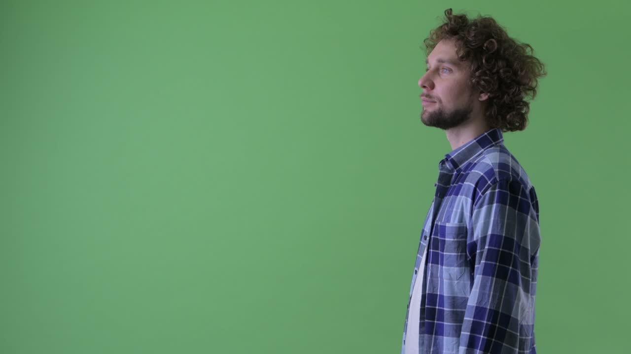 un joven guapo, barbudo y hipster con el cabello rizado.