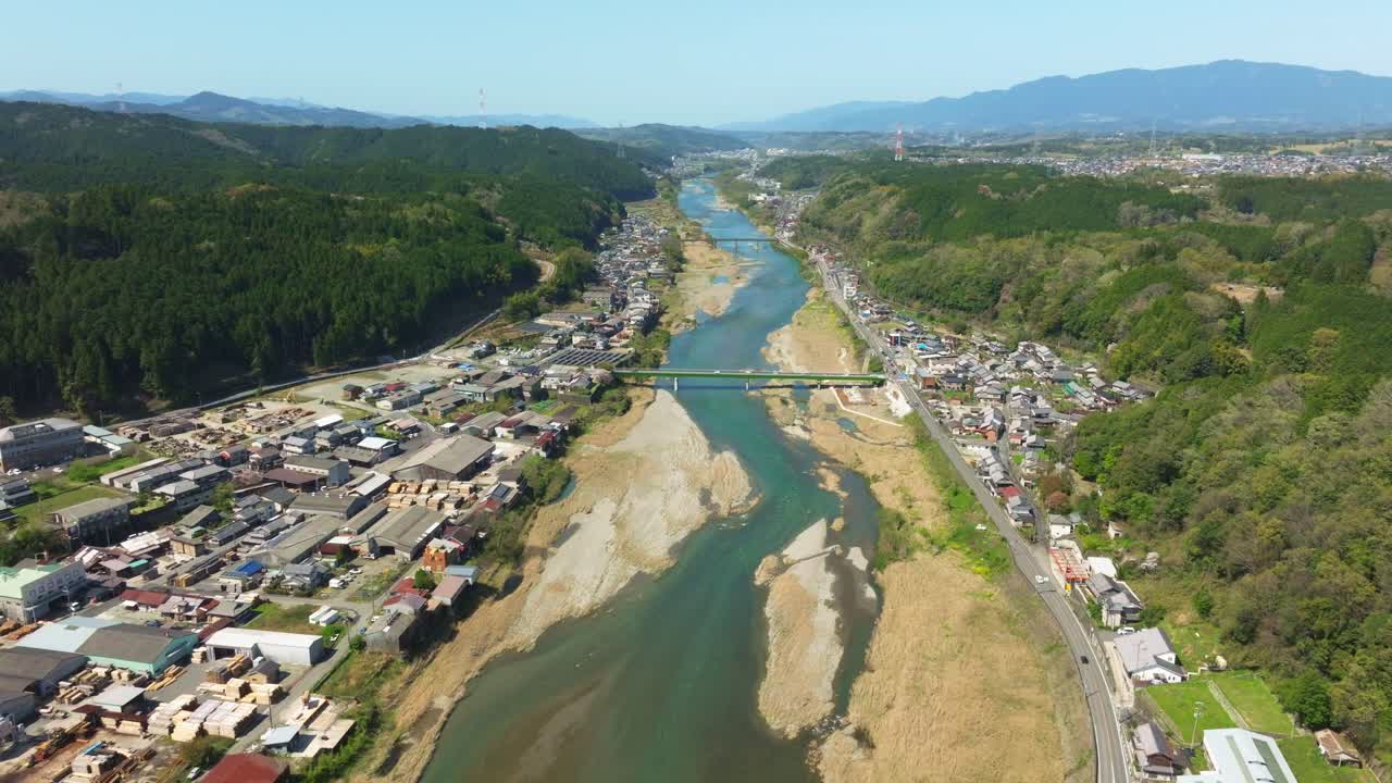 Aerial drone reveals a River getting dry in Japanese countryside landscape, valley village along vehicles traffic in the road