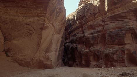 disparo de mano que revela una amplia abertura rodeada de paredes de piedra arenisca naranja que conduce a una estrecha entrada oscura al cañón de buckskin gulch en el sur de utah cerca de arizona en primavera