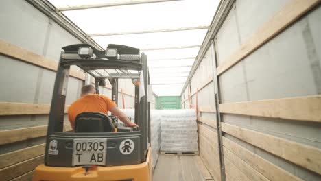 forklift driver transports packaged water bottles in warehouse