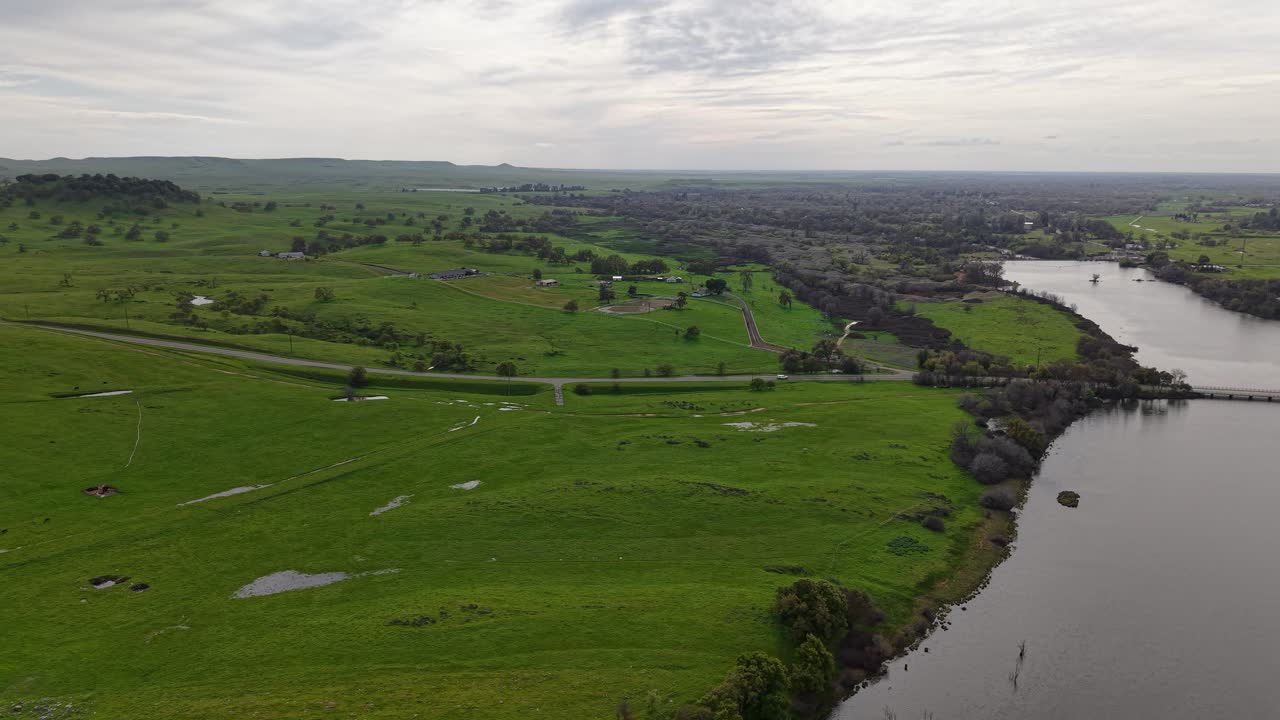 Rotating aerial view of Lake McSwain Dam and the surroundings of Merced California in the distance.
