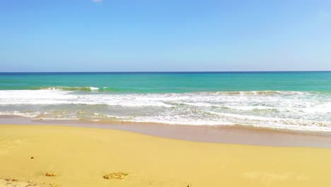 Tiefflug-Zwischen-Zwei-Hohen-Tropischen-Palmen-Am-Natürlichen-Sandstrand-In-Richtung-Weitläufiges-Grünes-Meerwasser-Und-Wellen,-Luftanflug