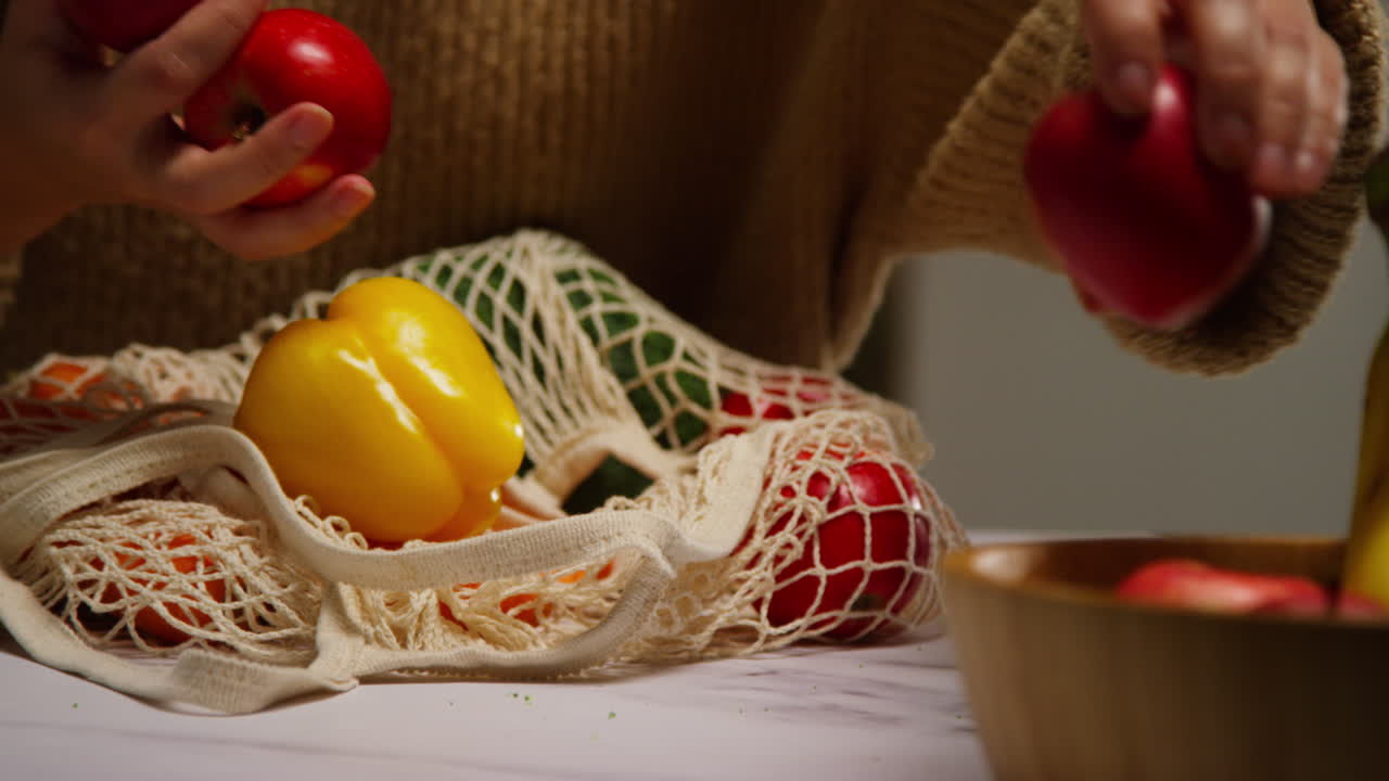 close up de una mujer desempaquetando una bolsa de frutas y verduras frescas y saludables en el mostrador en la cocina 5