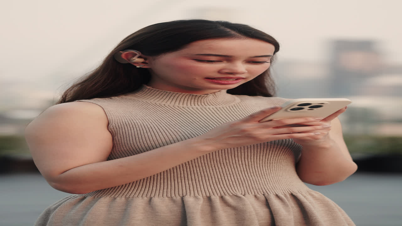 Giovane donna impegnata con lo smartphone all'aperto in un contesto urbano