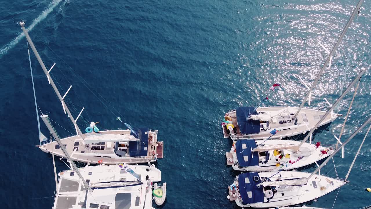 Vue par drone d'une croisière de yachts et d'un voilier en pleine mer bleue dans l'océan, 4K
