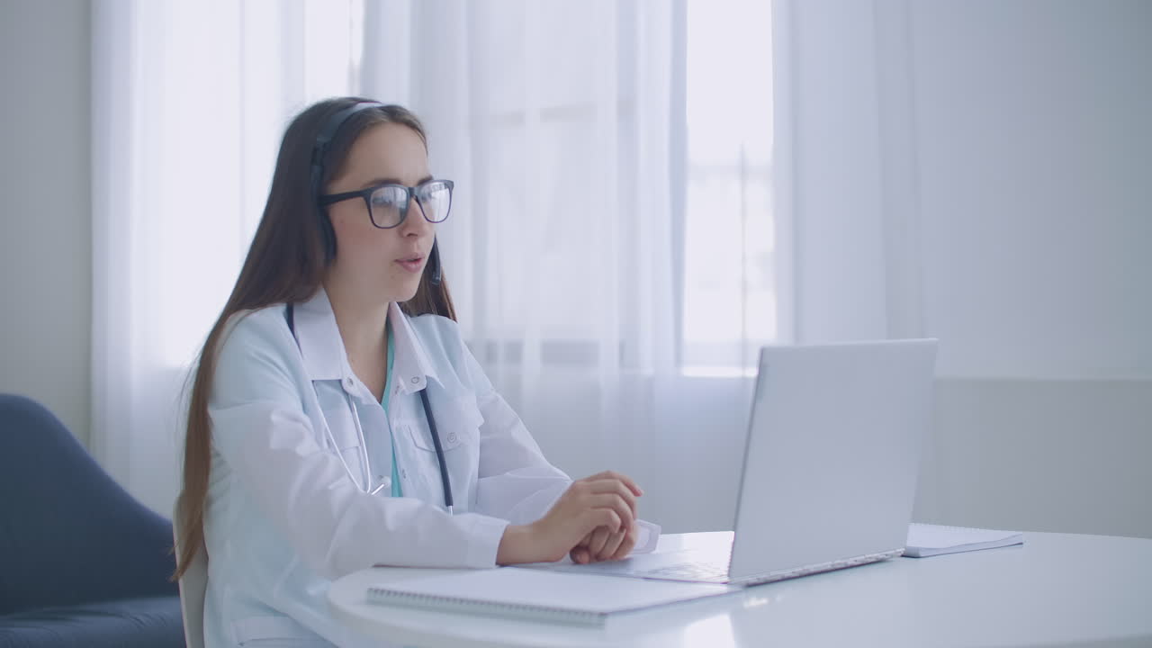 una asistente médica lleva una bata blanca con auriculares llamando a un paciente distante por computadora portátil. un médico hablando con un cliente usando una aplicación de computadora de chat virtual. concepto de servicios de atención médica remota de telemedicina.