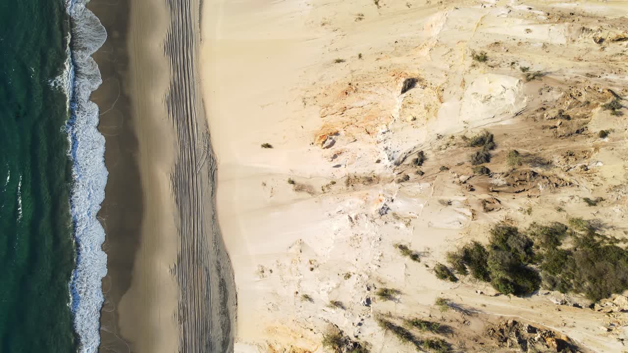 vista de drones mirando hacia abajo siguiendo una carretera de playa en 4x4 junto al océano y un acantilado empinado