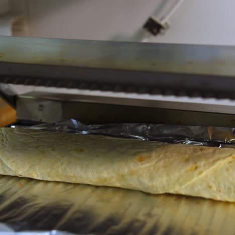 hands of cheef put shawarma on grill. preparing street food in cafe. tasty pita with vegatables and cheese