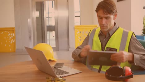 animación de un trabajador caucásico usando computadora portátil y tableta en la oficina
