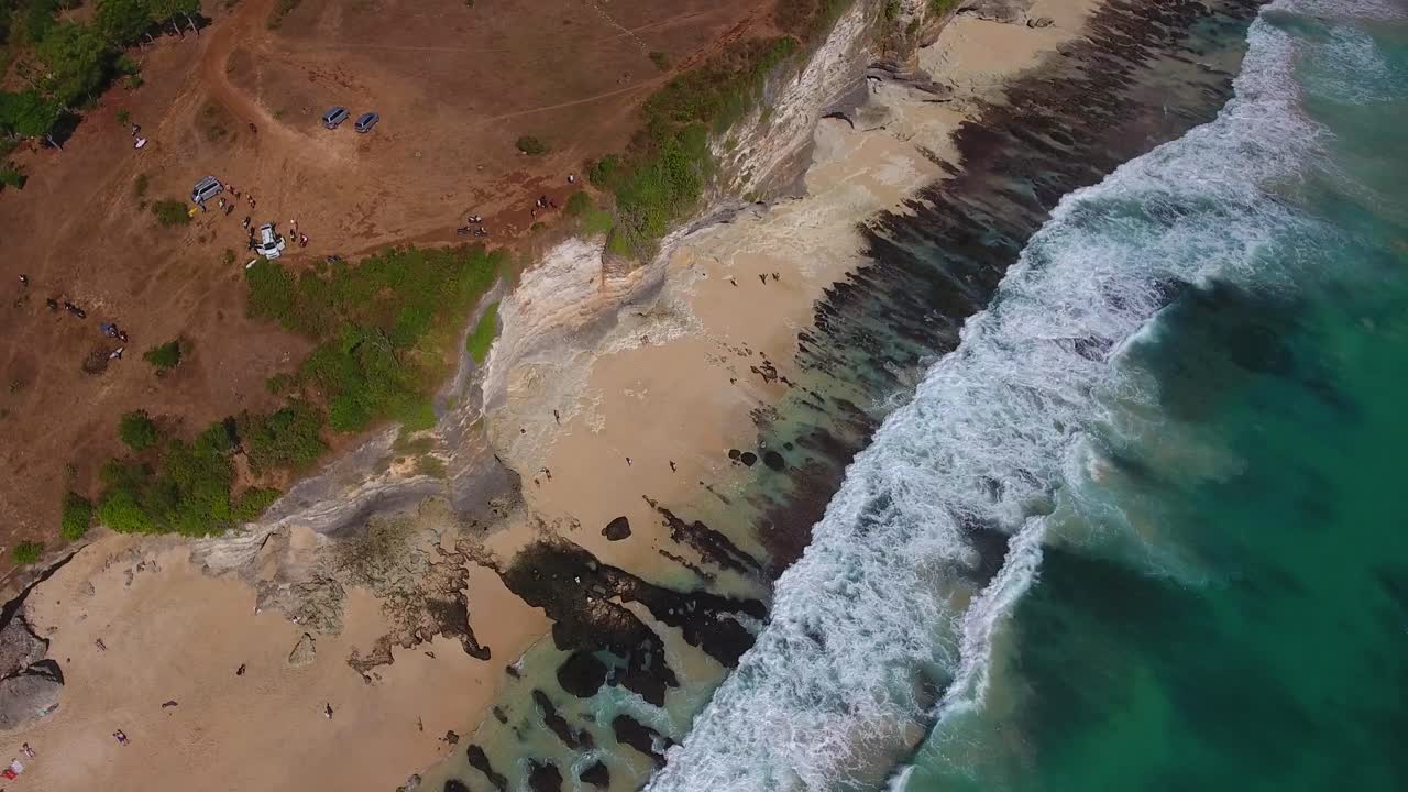 mirando hacia abajo la vista de las olas rodando hacia la playa rocosa con grandes acantilados, uluwatu, bali, indonesia