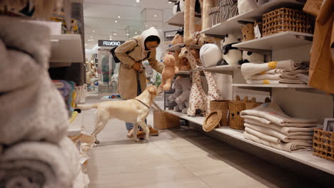 young girl shopping with a labrador at a dog friendly store and picking cute toys for her puppy